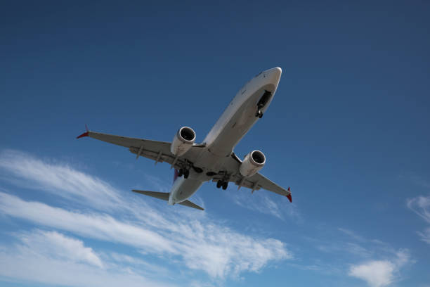 istock Modern white airplane flying in cloudy sky, low angle view 1479534625