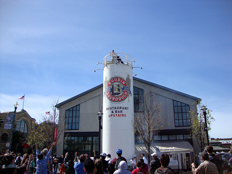San Francisco - March 14, 2010:  A man throws bread off the top of Boudin Sourdough to a crowd of people in Fisherman's Wharf. The tradition is said to have originated in the 1920s, when a Boudin employee would throw bread to the seagulls that would gather around the shop. The practice has since become a popular tourist attraction.