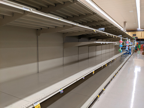 Empty shelves in the supermarket vegetable aisle, during a shortage of tomatoes and cucumbers.