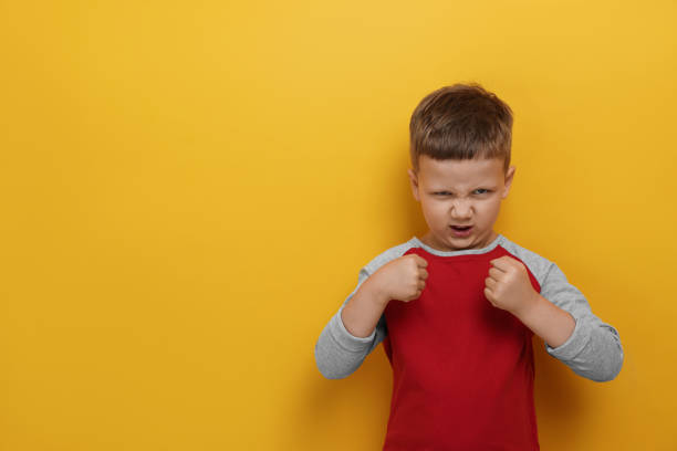 istock Angry little boy on yellow background, space for text. Aggressive behavior 1479537778