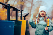 Little Girl Throwing a Plastic Bottle in the Recycle Bin