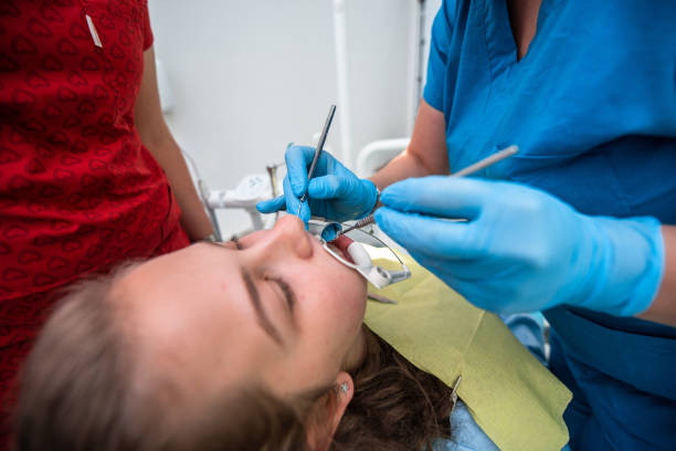 istock Dentist appointment at a dental clinic, placing braces locks on the teeth and pulling the archwire to fix it 1479541584