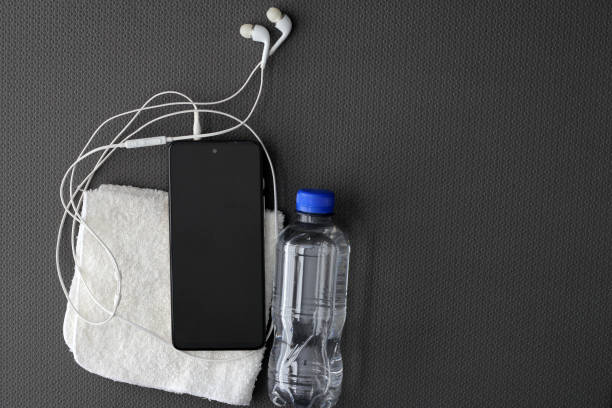 istock Mat to exercise with the necessary objects such as wireless headphones, cell phone, apple, water to hydrate, sweat towel and locker keys 1479542557