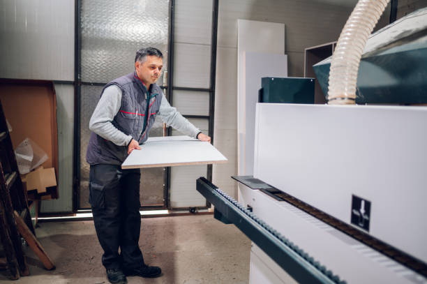 istock A worker is holding a big wooden panel and preparing to put it in a wood processing machine. 1479545139