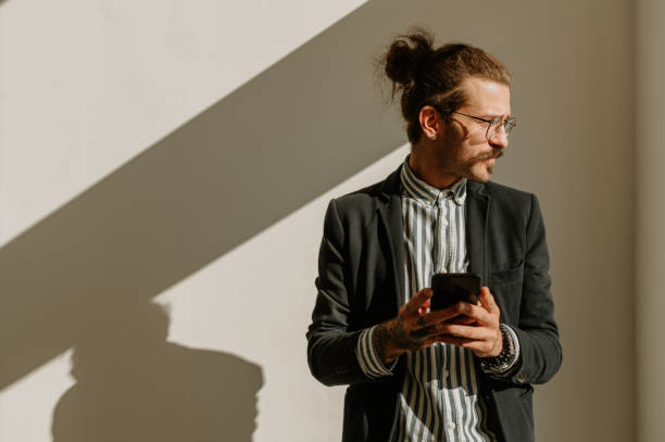 istock Businessman using smartphone while standing over a white wall in an office 1479545161