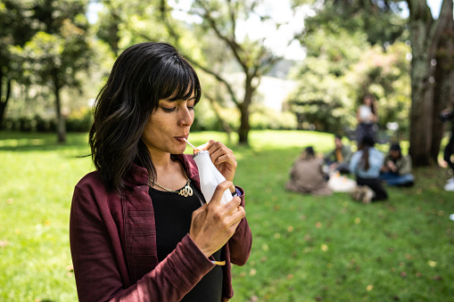 Mid adult woman drinking yogurt at public park
