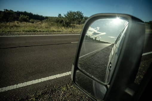 An empty route is seen in the side mirror of the vehicle.