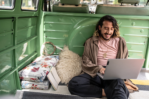 Young man using laptop inside in a retro mini van