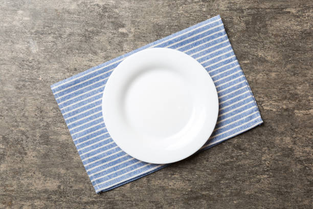 istock Top view on colored background empty round white plate on tablecloth for food. Empty dish on napkin with space for your design 1479554086