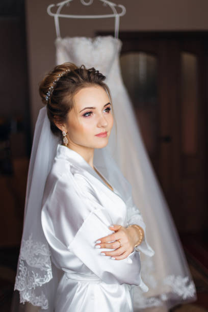 istock bride in white bathrobe with make up and bridal veil crossed arm 1479554563