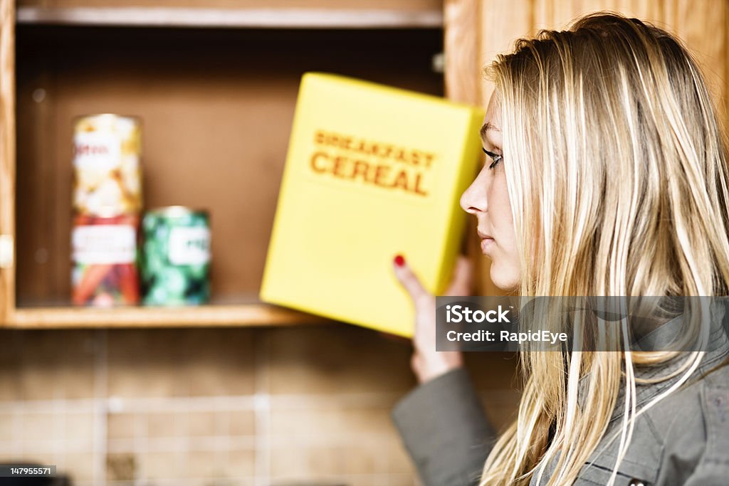Bella donna mette cereali di distanza o si è fuori! - Foto stock royalty-free di Armadietto da cucina