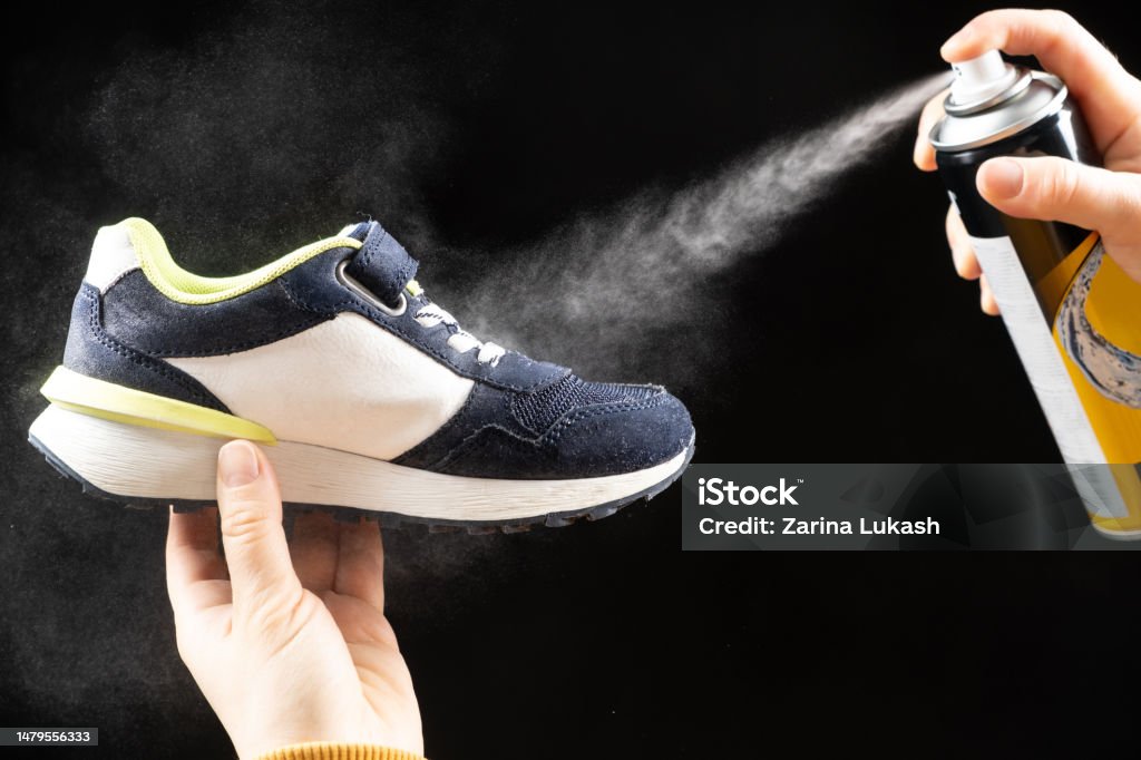 Una Mujer Aplica Un Aerosol De Un Cilindro Con Un Líquido Repelente Al Agua  Al Zapato De Los Niños Cuidado De Los Zapatos Eliminación De Olores  Desagradables Foto de stock y más
