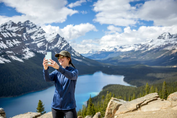 Young Woman Taking Picture or Selfie at Peyto Lake, Banff, Alberta, Canada stock photo