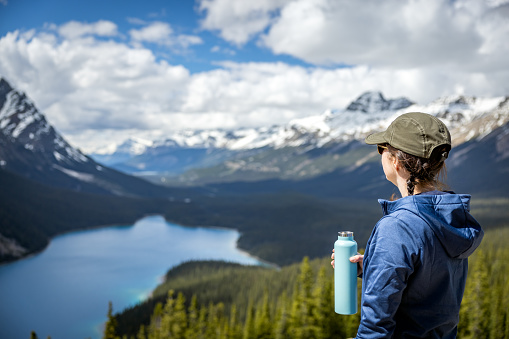 Young Woman Looking at the View of Peyto Lake in Banff National Park, Alberta, Canada. She is drinking water in a reusable water bottle.
