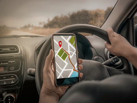 Car driver using smart phone with GPS map navigation while driving, car sharing app concept