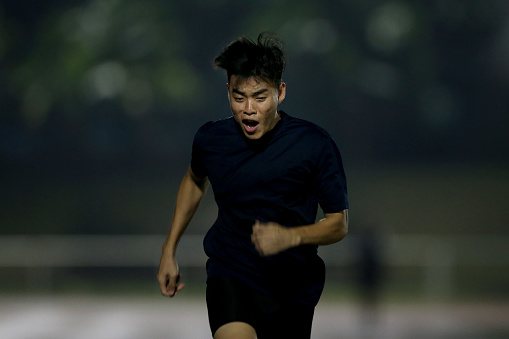 An Asian young athlete is focusing in 100m track and field race.