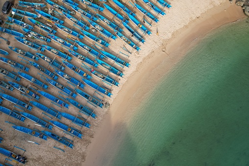 aerial photography of white sandy tropical beach with blue fishing boats lined up neatly on the shore. clear watery beach, green tosca. Pantai Ngrenehan in Gunungkidul Yogyakarta Indonesia.