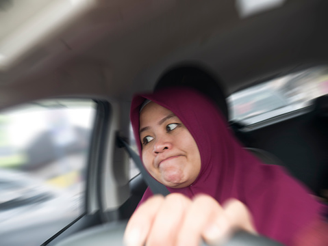 Portrait of Asian muslim female driver mad of trapped in traffic jam,  mischievous reckless way of driving concept with motion blur