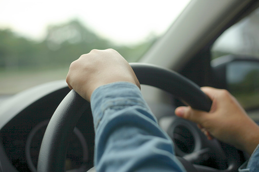 Hands of driver on steering wheel, driving a car concept, close up image with selective focus