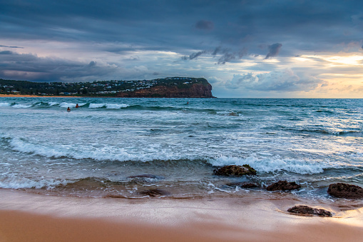 Sunrise seascape with rain clouds and rocks at Macmasters Beach on the Central Coast, NSW, Australia.