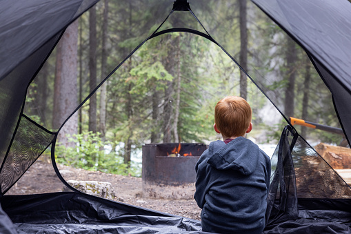 Young Redhead Boy Inside a Tent at Camping Site Close to Campfire, Yoho National Park, Bc, Canada