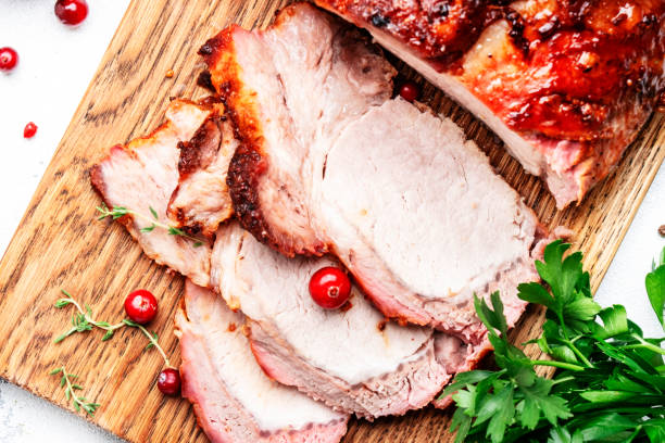 istock Baked cold boiled pork on cutting board with spices, herbs and cranberries. White kitchen table background, top view 1479575987