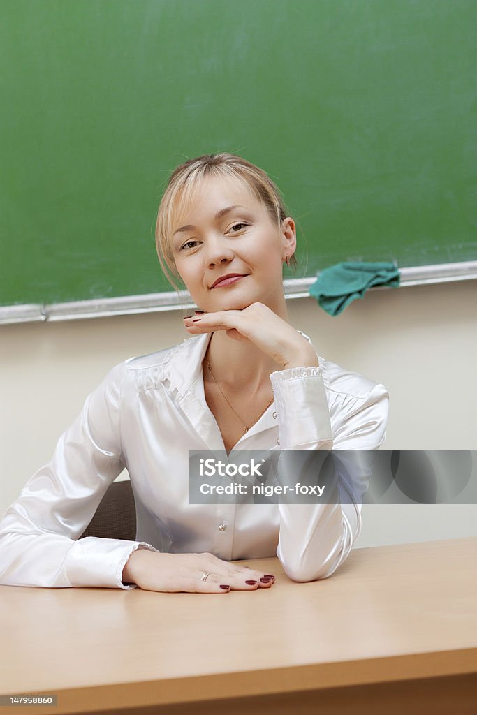 teacher in classroom The teacher in the classroom on blackboard background. Adult Stock Photo