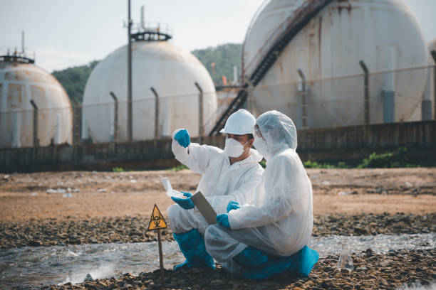 Il biologo indossa una tuta protettiva e la maschera raccoglie campioni di acque reflue dall'industria - foto stock