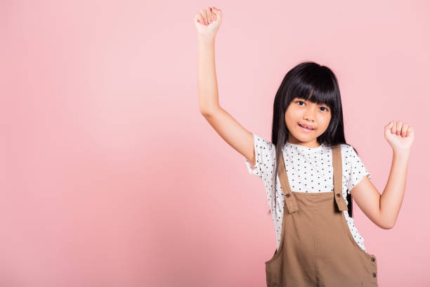 petit enfant asiatique de 10 ans célébrant un grand succès avec les bras levés - female 8 9 years child excitement photos et images de collection