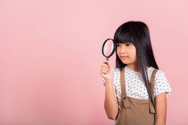 istock Asian little kid 10 years old funny looking through magnifying glass 1479589042