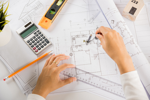 Architectural project workplace. Engineer sketching construction project, Architect drawing with divider compass on house plan blueprint paper for repair tools on table desk at architecture office