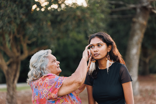 Aboriginal Australian Grandmother and Granddaughter Doing Traditional Ochre Face Painting