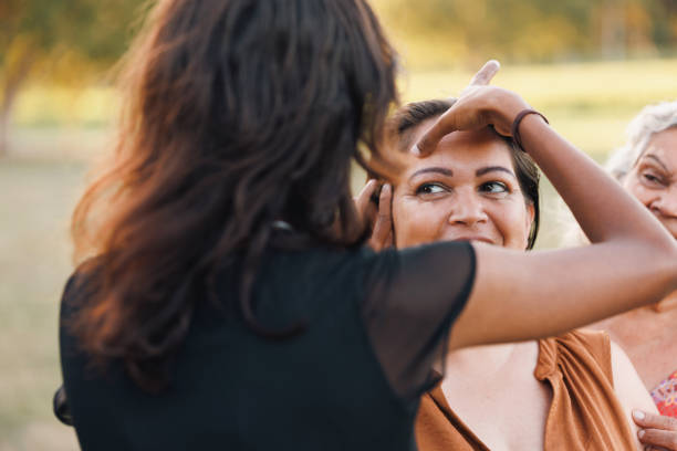 Three Generations Of Aboriginal Australian Women Doing Traditional Ochre Face Painting