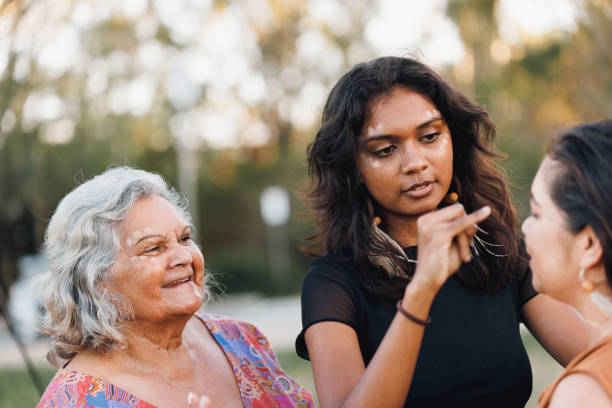 Three Generations Of Aboriginal Australian Women Three Generations Of Aboriginal Australian Women Doing Traditional Ochre Face Painting aborigine woman stock pictures, royalty-free photos & images