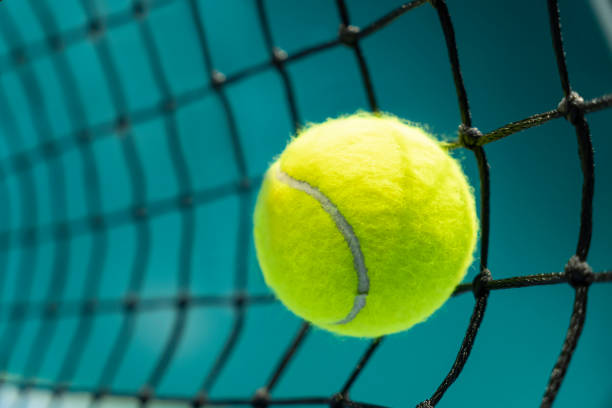 bola de tênis atingiu uma rede preta no fundo de uma quadra de tênis - tennis court indoors net - fotografias e filmes do acervo