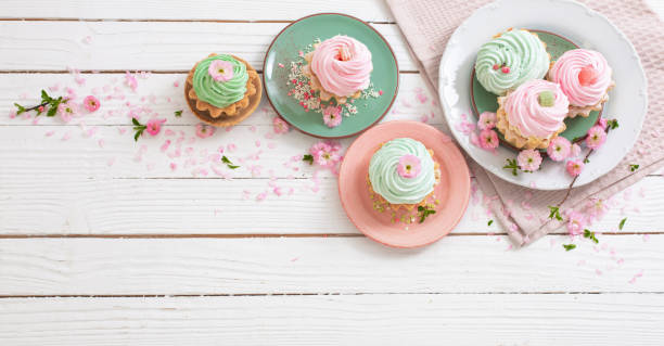 istock pink and green cupcakes with spring flowers on white wooden background 1479594021