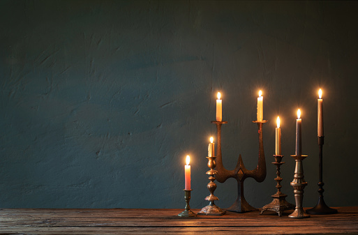 burning candles in vintage candlesticks on dark background