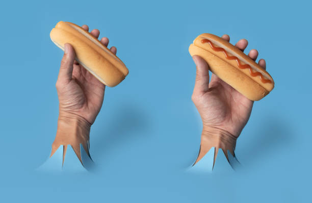istock Hand hold uncooked hotdog through blue paper background. 1479595341