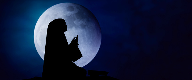 Silhouettes Muslim woman praying with the Moon background