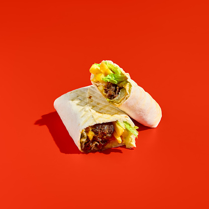 Square minimalist composition of beef shawarma with french fries on a red background. Modern food photography and takeout concept.