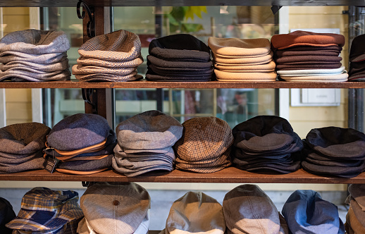 Varieties of caps and hats for men on the shelf of a clothing shop. Peaky blinders style hats. 1920s years style. Nobody, street photo, selective focus