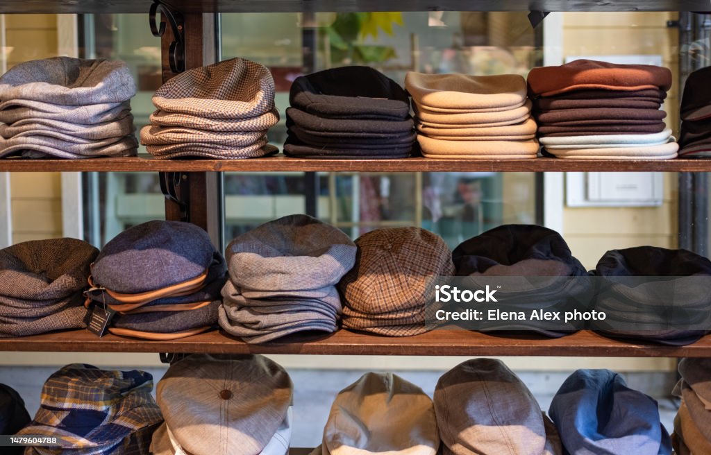 Varieties of caps and hats for men on the shelf of a clothing shop. Peaky blinders style hats. 1920s years style. Varieties of caps and hats for men on the shelf of a clothing shop. Peaky blinders style hats. 1920s years style. Nobody, street photo, selective focus Flat Cap Stock Photo