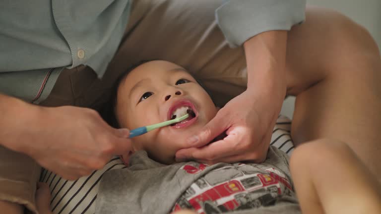 Father brushing teeth for kid