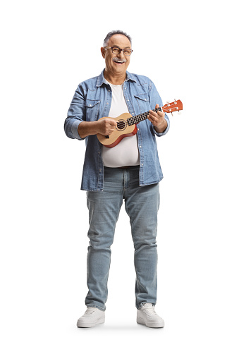 Full length portrait of a mature man playing ukulele isolated on white background