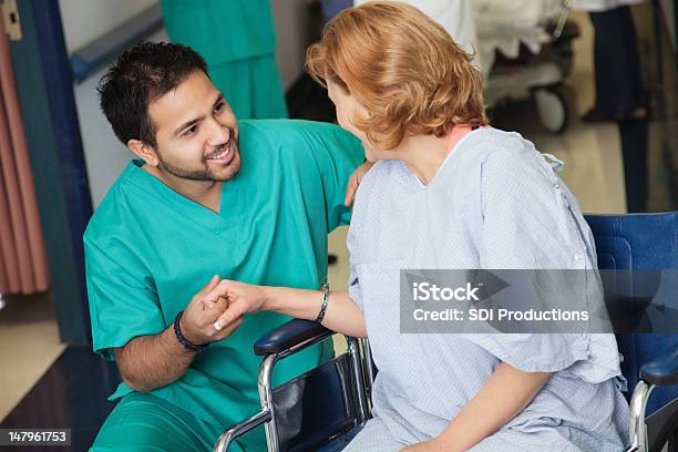 Masculino Enfermeira Ajuda Paciente Em Cadeira De Rodas No Hospital - Fotografias de stock e mais imagens de Enfermeiro