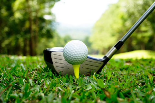 Golf club and golf ball in beautiful golf course with blurred background.