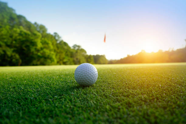 golfball auf grün in wunderschönem golfplatz bei sonnenuntergang im hintergrund. golfball auf grün auf golfplatz in thailand - golf golf flag sunset flag stock-fotos und bilder