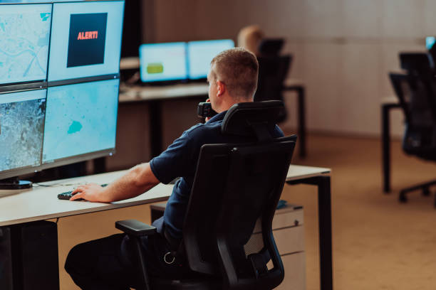 istock Group of Security data center operators working in a CCTV monitoring room looking on multiple monitors.Officers Monitoring Multiple Screens for Suspicious Activities 1479621829