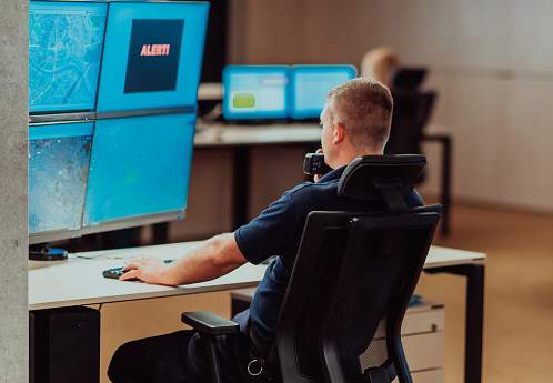 Group of Security data center operators working in a CCTV monitoring room looking on multiple monitors.Officers Monitoring Multiple Screens for Suspicious Activities.