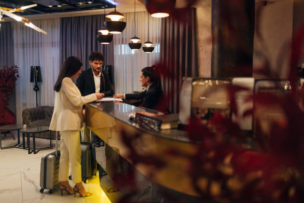 istock Smiling receptionist helping a hotel guests check in pointing to information on the form that needs to be completed as they stand at the service desk in the lobby 1479625212